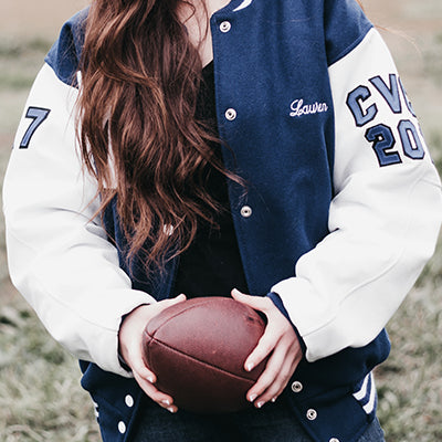 A female athlete wearing a Letterman jacket.