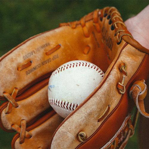 A leather baseball glove holding a baseball.