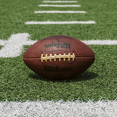 A Wilson football on a field with yard lines.