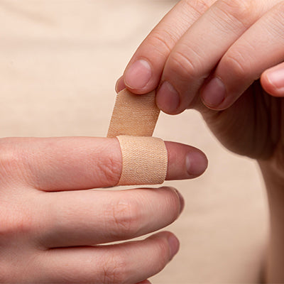 Someone applying a band aid to a finger.